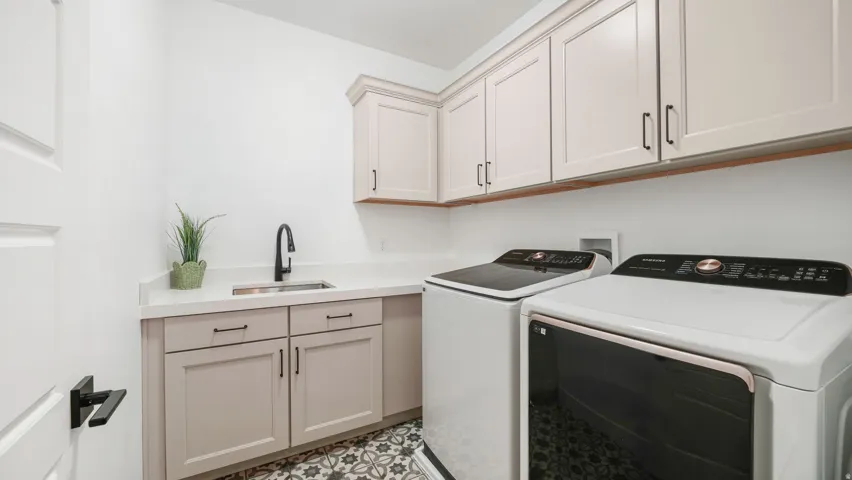 Laundry room featuring patterned floor tile, light cabinetry, a utility sink with a matte black faucet, and a white countertop