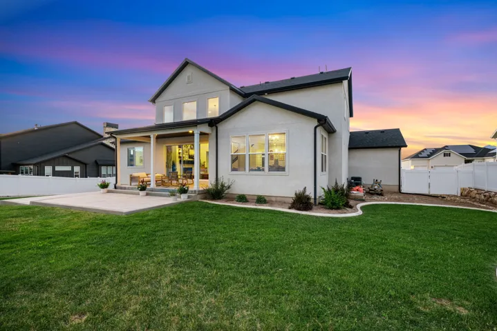 Expansive backyard featuring a manicured lawn, a concrete patio, and a covered patio area with recessed lighting