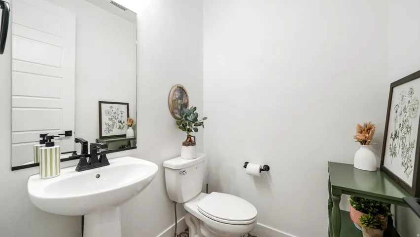 Pedestal sink with a black-finish faucet and rectangular wall mirror