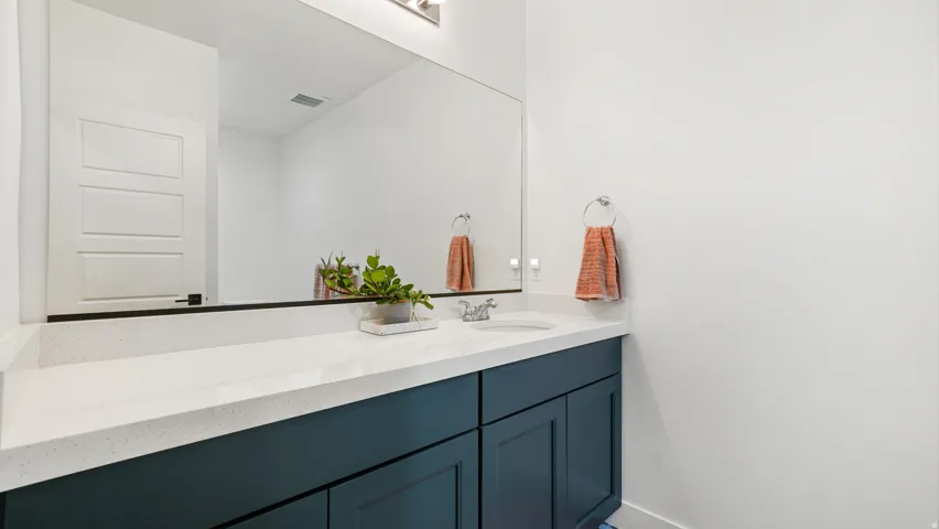 White countertop with an integrated sink and a dark blue vanity cabinet featuring two doors