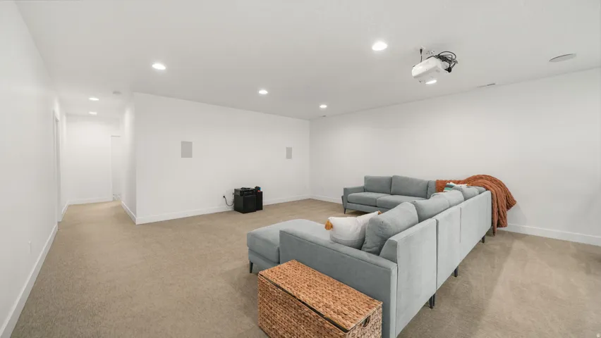 Spacious room featuring neutral carpeting, recessed lighting, and a ceiling-mounted projector