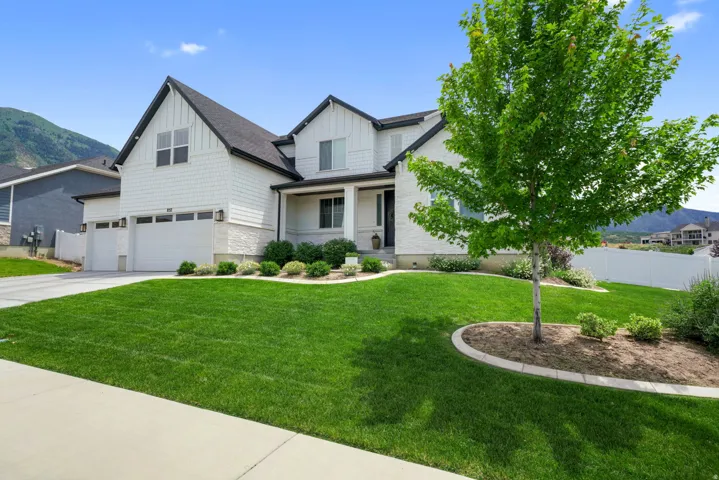 Modern farmhouse-style residence featuring white siding, dark trim, and a prominent front-facing garage