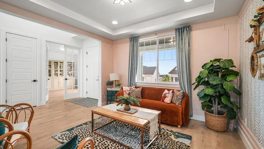 Inviting living area featuring a large window, light wood-finish flooring, recessed lighting, a tray ceiling, and French doors