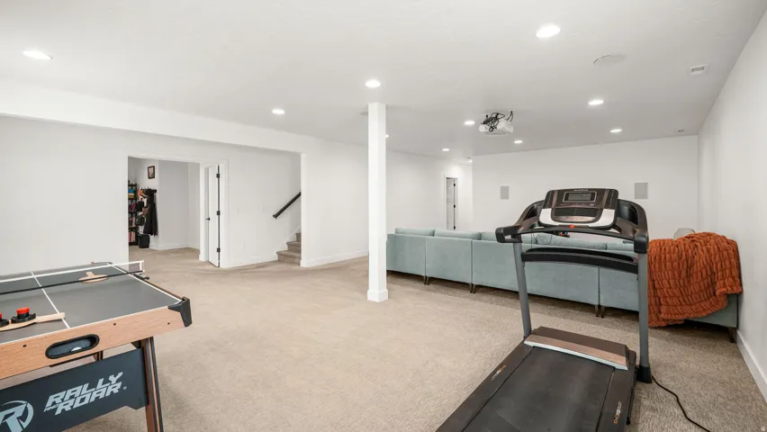 Expansive finished basement with recessed lighting, carpeted flooring, and a built-in projector