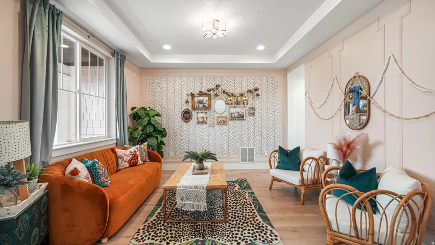 Spacious living area featuring light wood-finish flooring, a tray ceiling with recessed lighting, and a prominent window