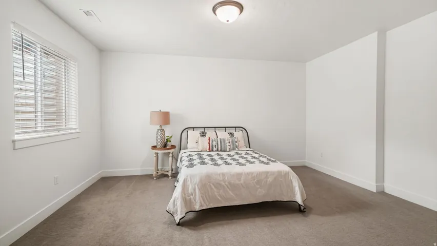 Spacious room featuring neutral carpeting, white walls, and a window with blinds