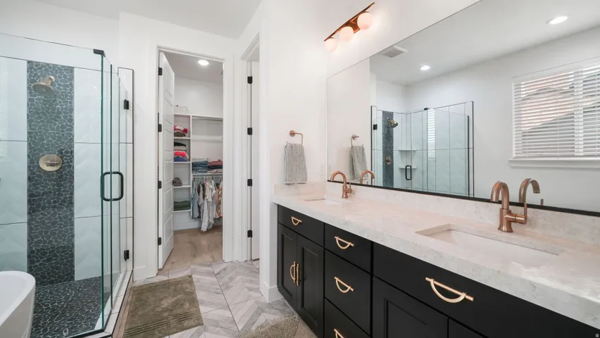 Contemporary bathroom featuring a dual vanity with quartz countertops, custom dark cabinetry, and gold-tone fixtures
