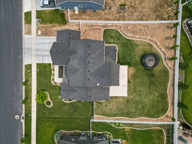 Expansive property featuring a multi-gabled roofline, a concrete driveway, an elongated patio, and a perimeter fence enclosing the backyard