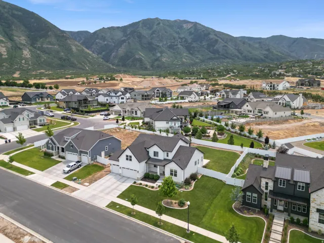 Contemporary residential community featuring diverse architectural styles, manicured lawns, paved streets, and a prominent mountain backdrop