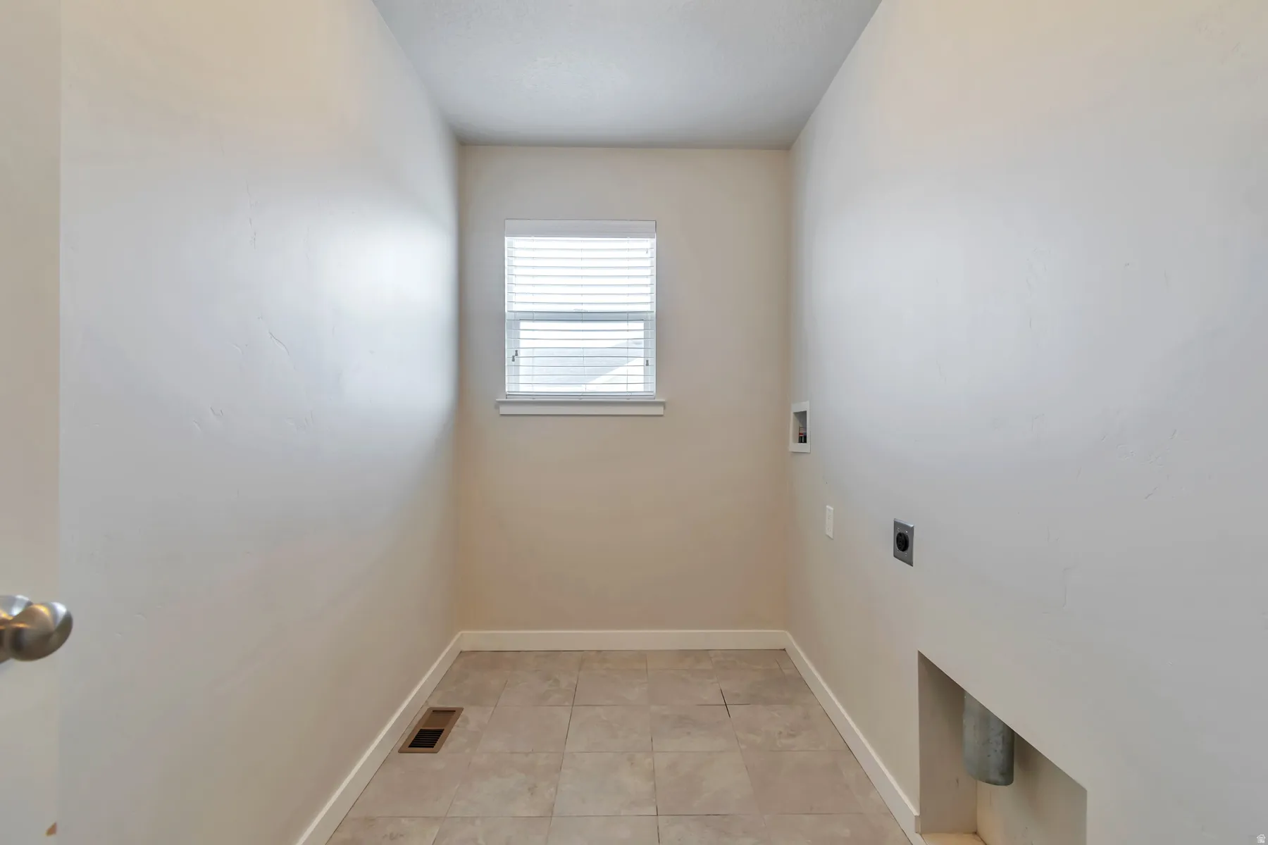 Laundry room featuring tile flooring, a window with blinds, and appliance hookups