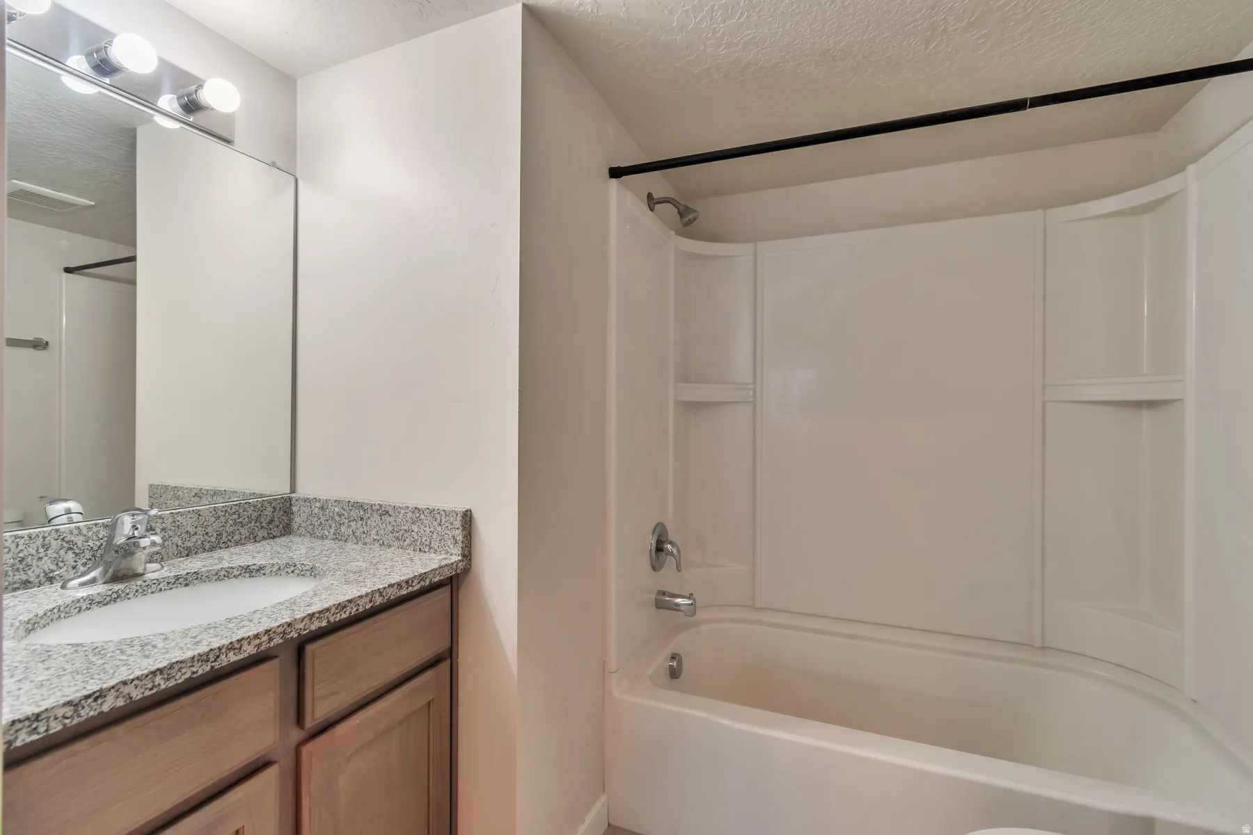 Bathroom featuring a vanity with a light-colored countertop, an undermount sink, and wood-finish cabinetry
