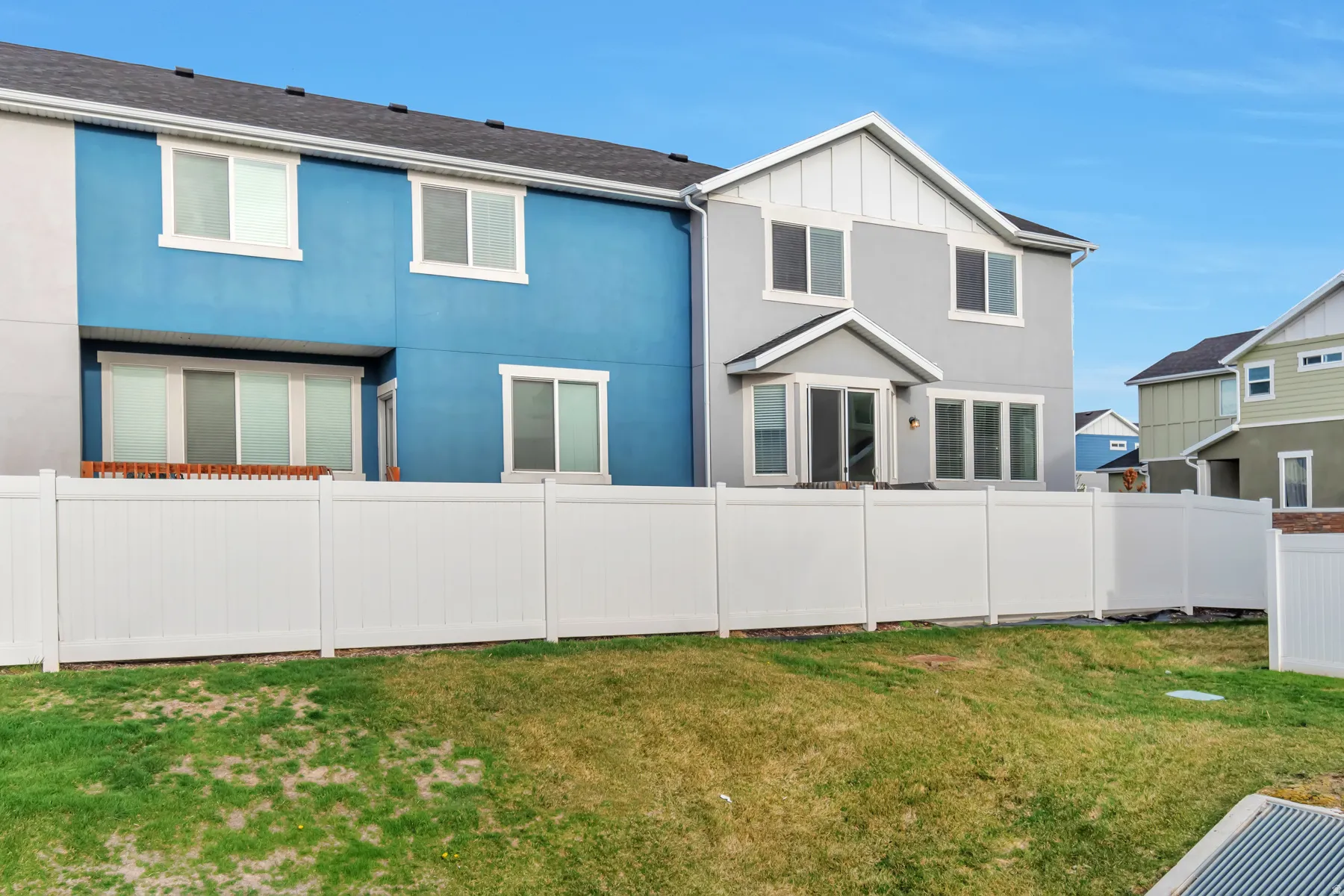 Exterior featuring a two-story design with stucco siding, a white privacy fence, multiple windows, and a sliding glass door