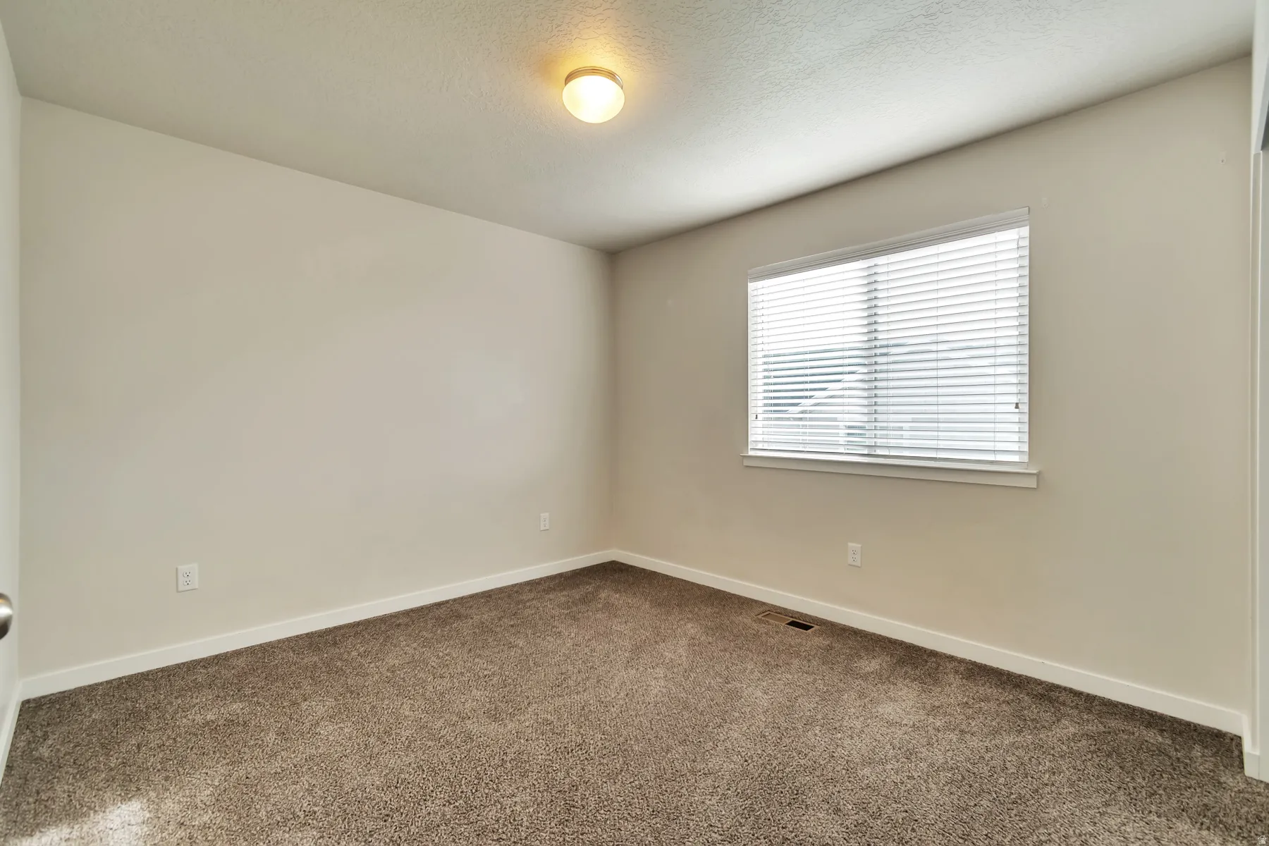 Neutral tone wall paint with a single window featuring horizontal blinds