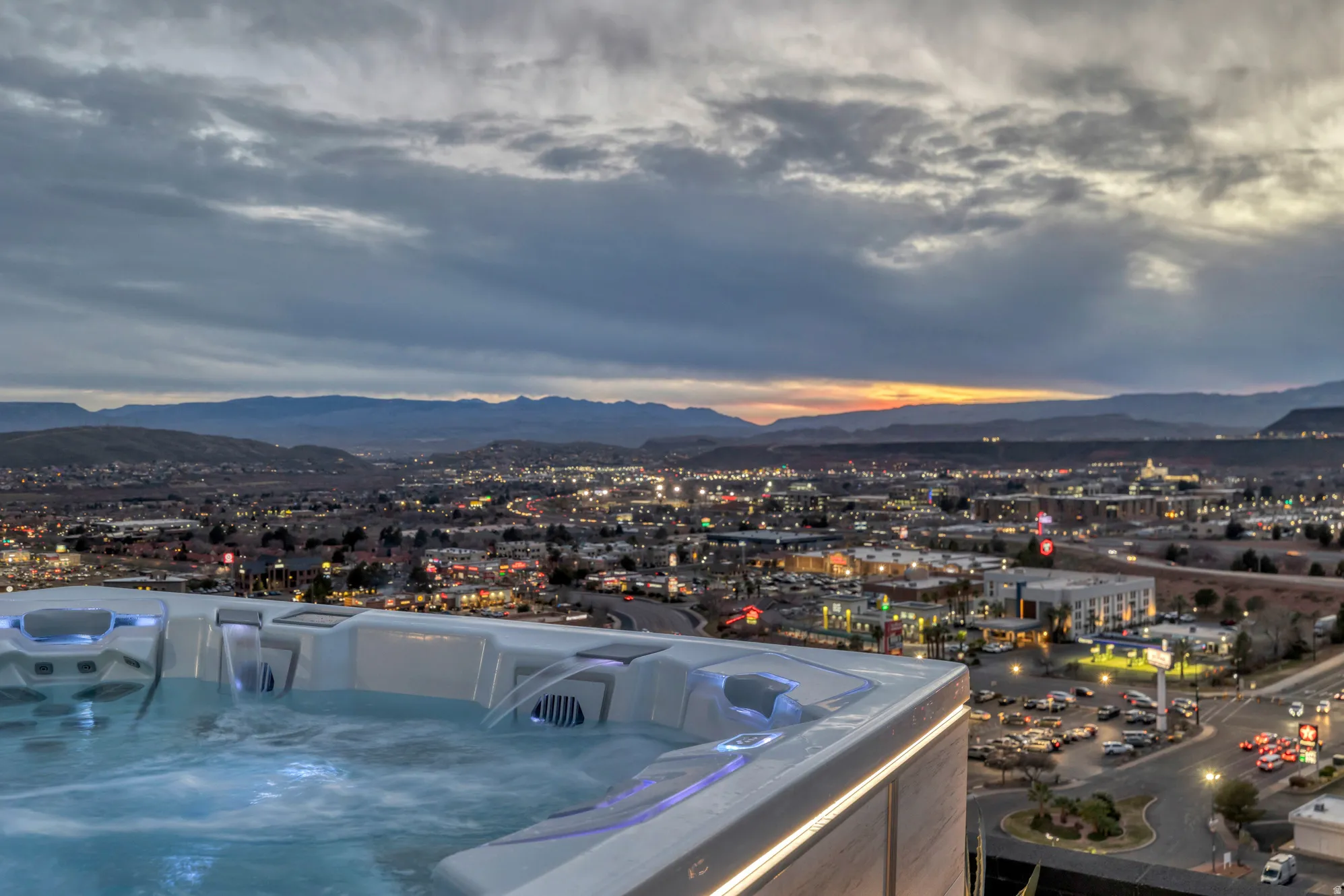 Rooftop hot tub with integrated lighting and water features, offering expansive city and mountain scenery