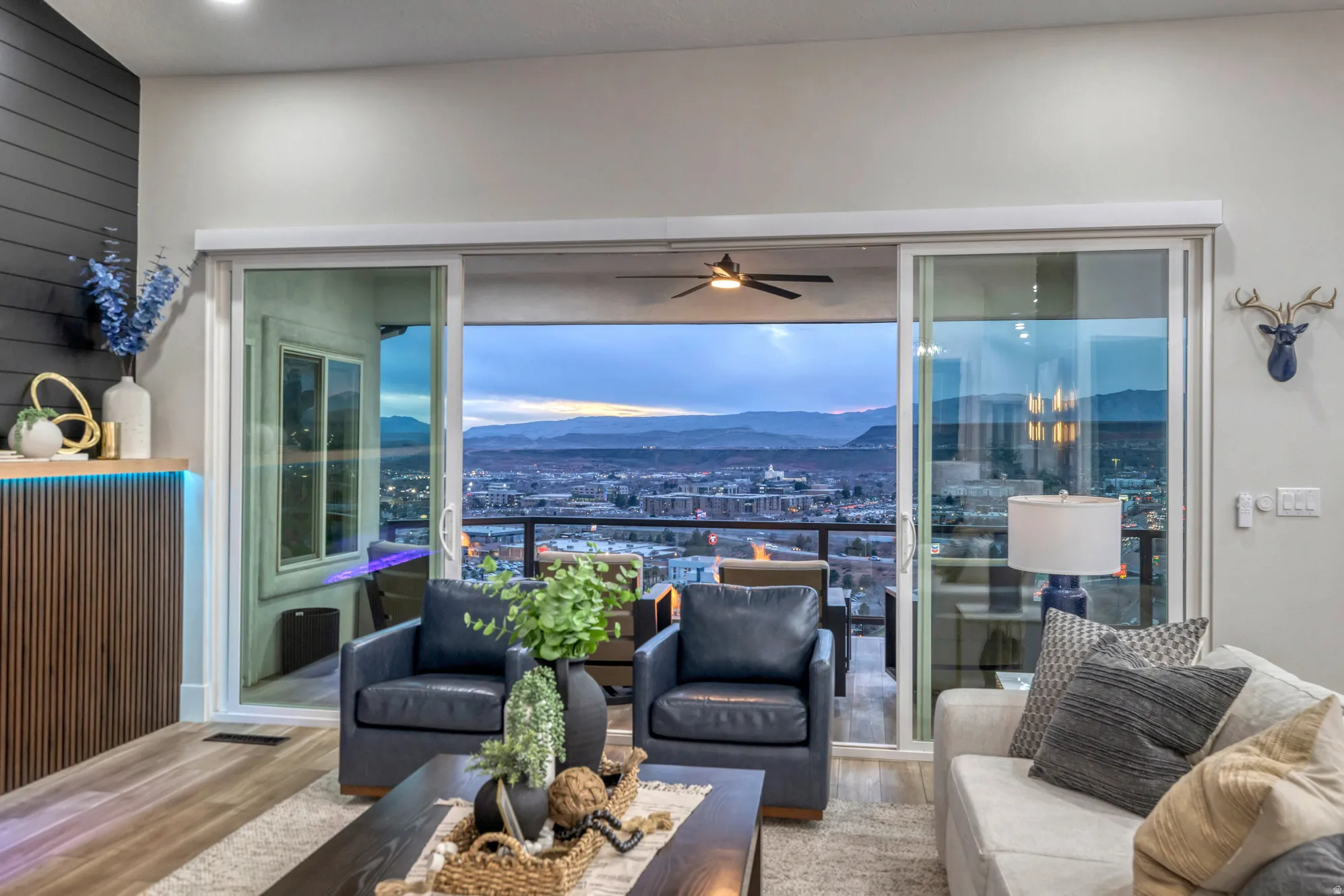 Expansive glass sliding doors open to an outdoor balcony with mountain and city backdrops
