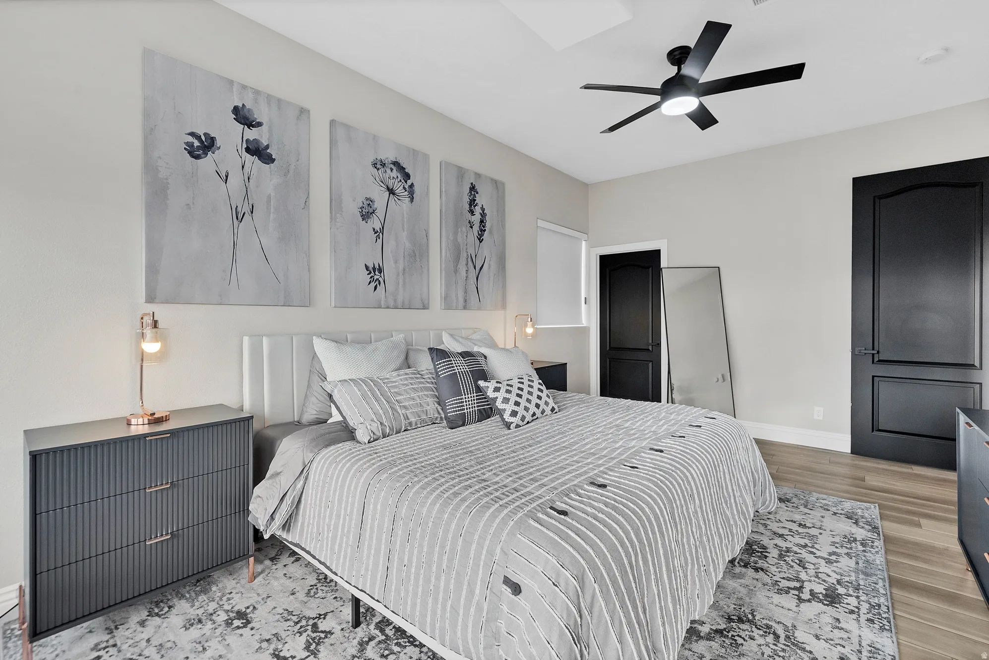 Bedroom featuring a contemporary ceiling fan, light-colored walls, and wood-finish flooring