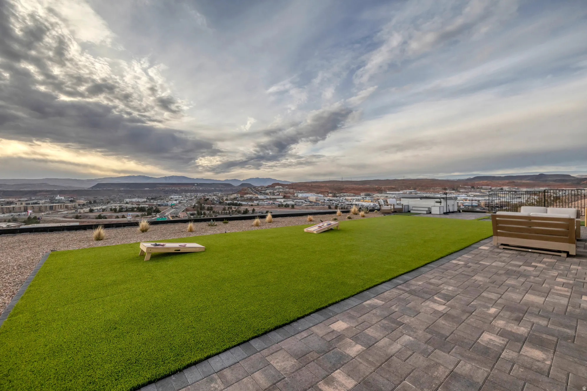 Rooftop patio featuring extensive paver surfacing, artificial turf, a gravel border, and a black metal railing