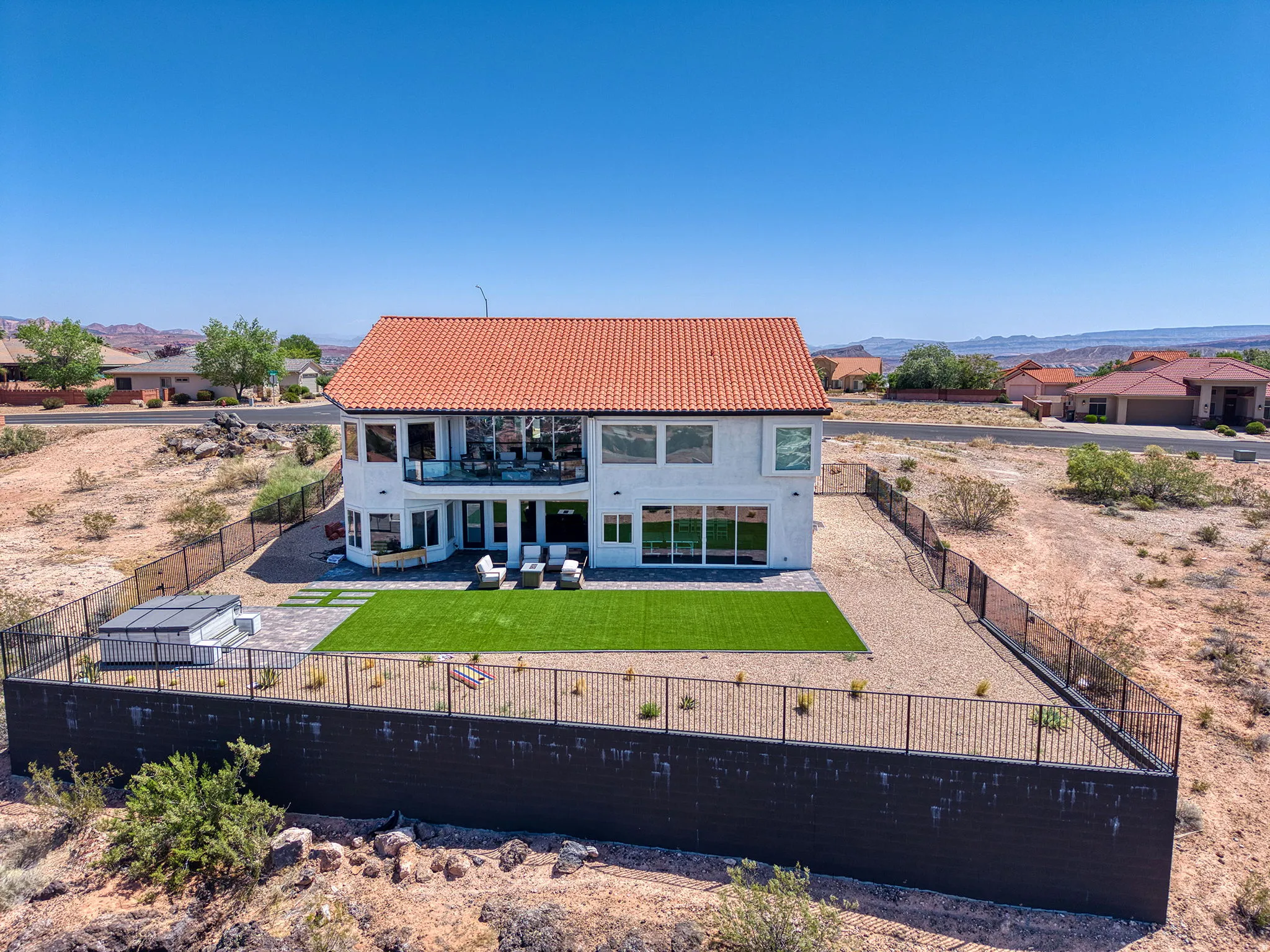 Mediterranean-style home featuring a terracotta tile roof and extensive rear fenestration