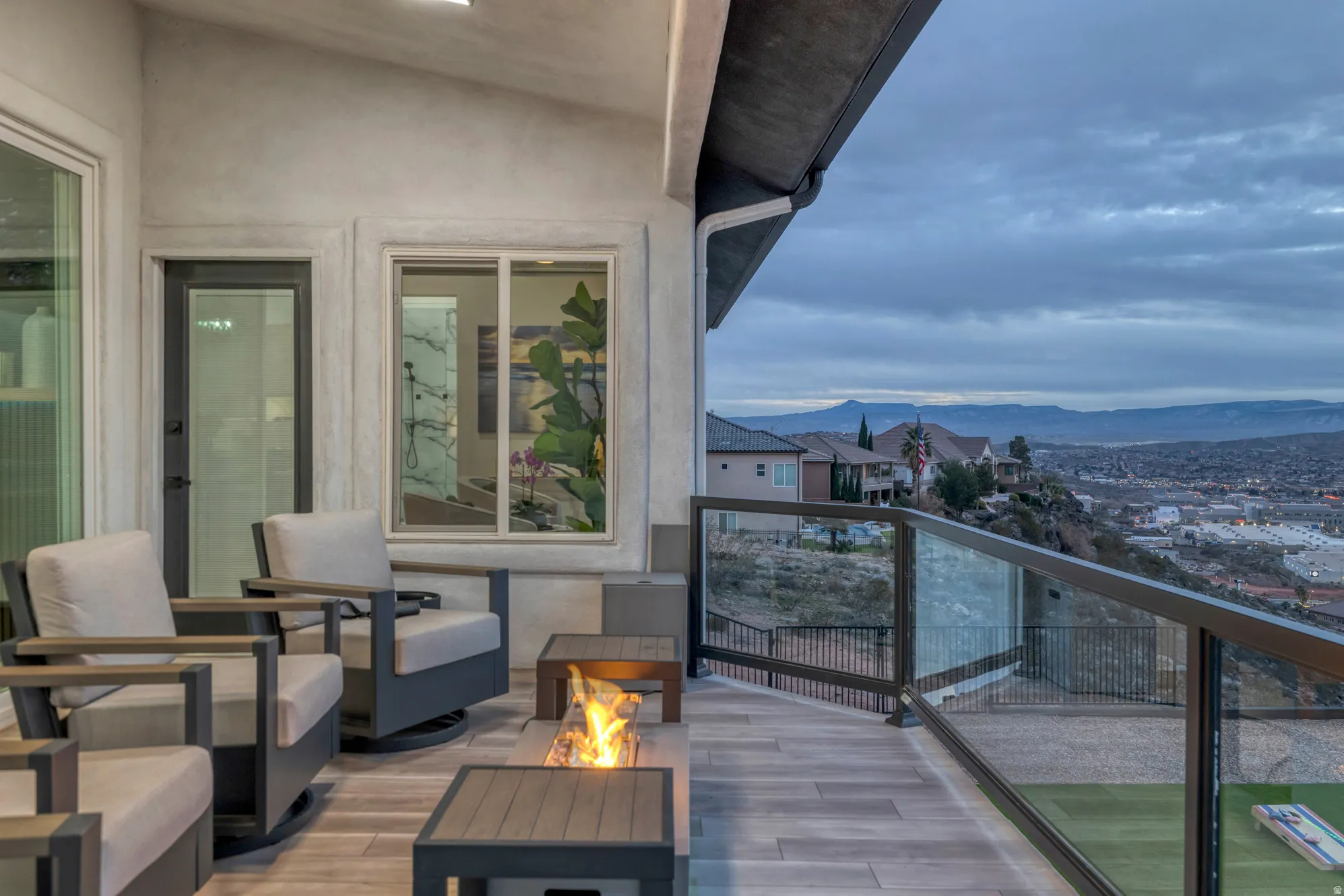 Spacious outdoor patio featuring wood-finish flooring, a built-in fire pit, and a glass-paneled railing