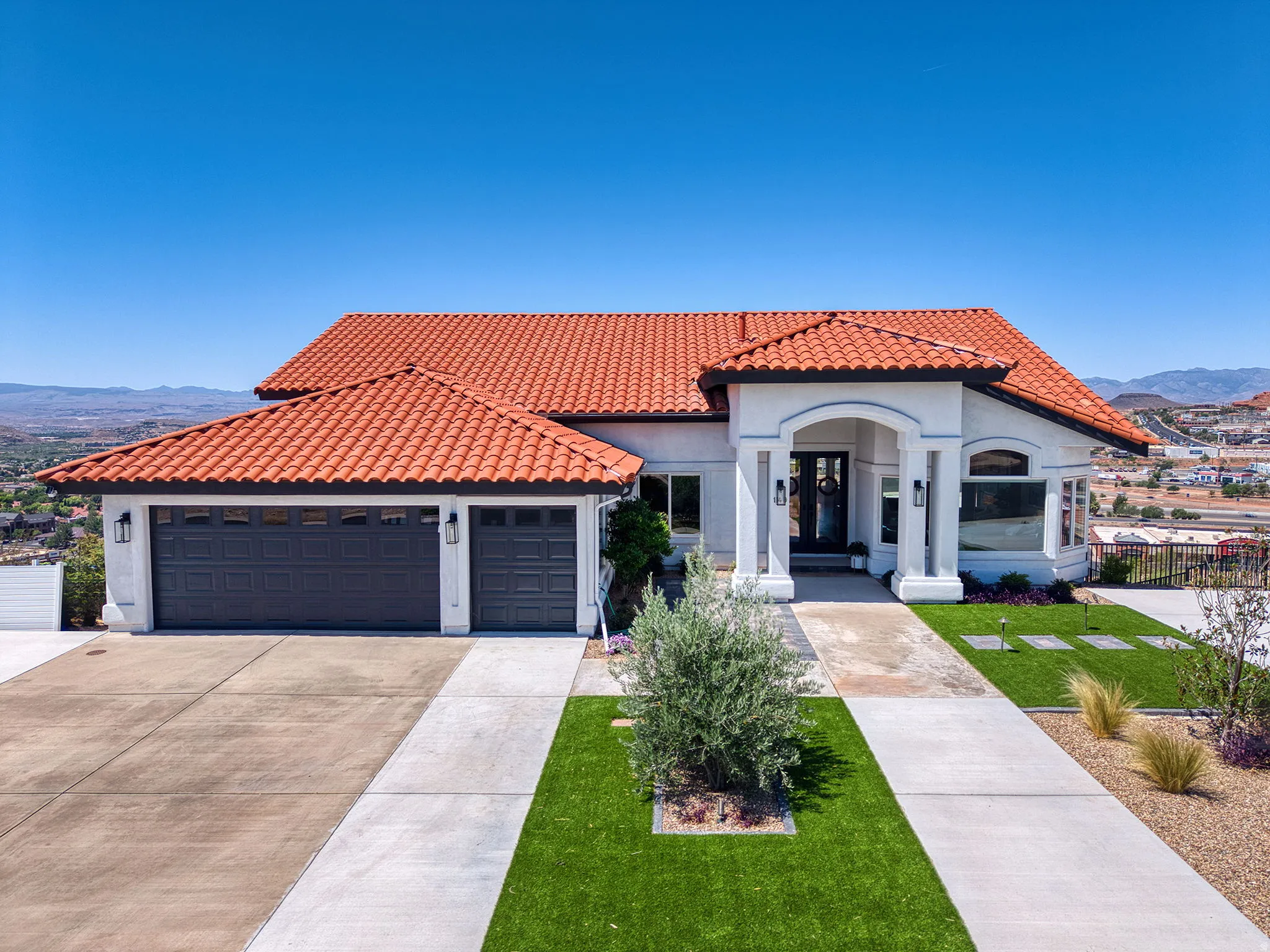 Mediterranean-style residence featuring a distinctive red tile roof, white stucco exterior, and black trim accents