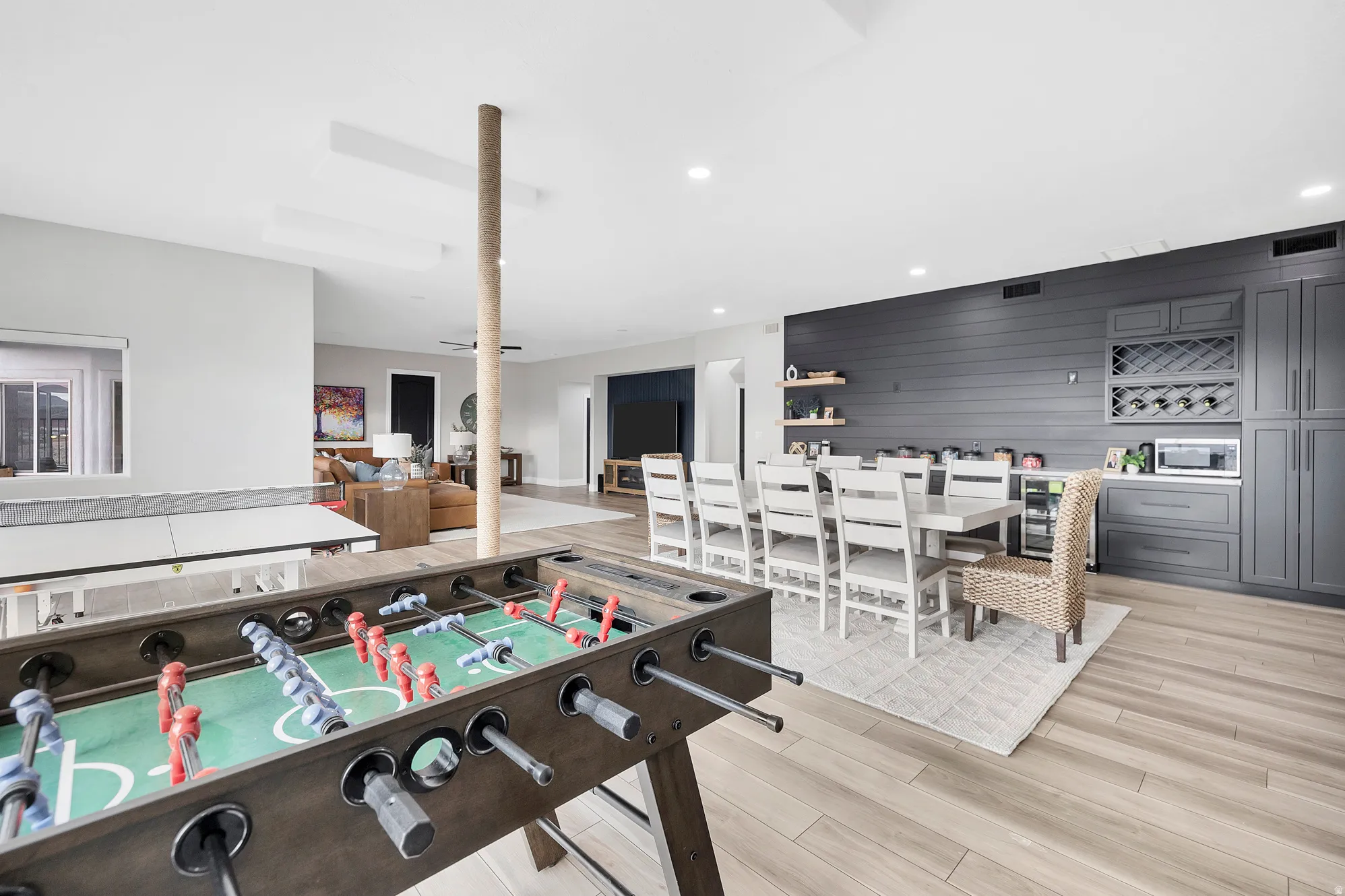 Open-concept entertainment area featuring light wood-finish flooring, recessed lighting, and a neutral color palette