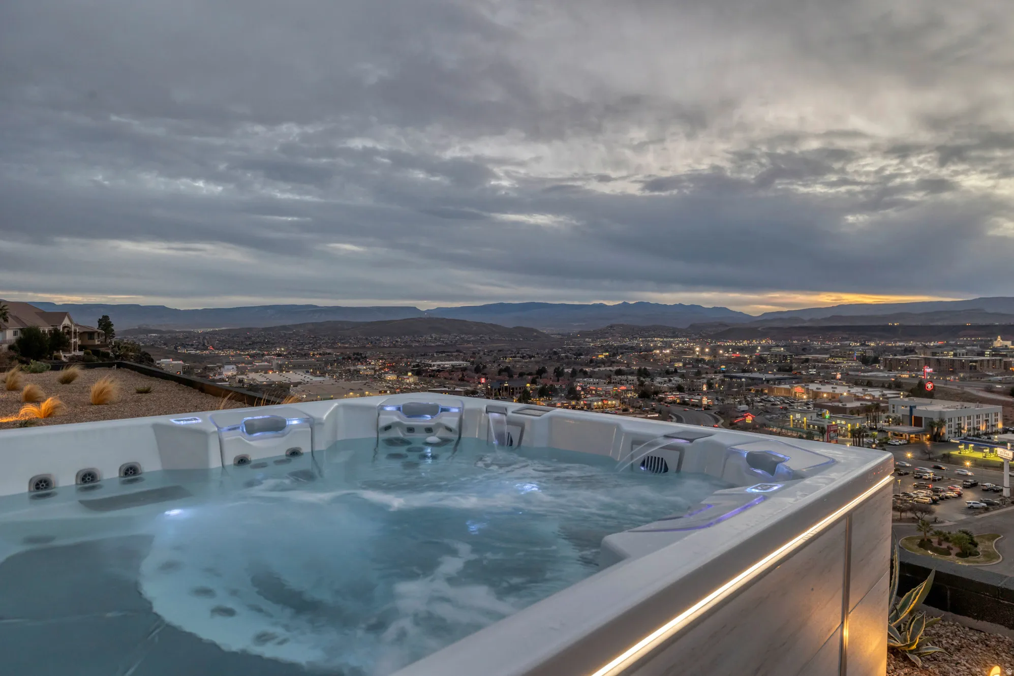 Outdoor spa with integrated lighting, showcasing an expansive cityscape and distant mountain ranges