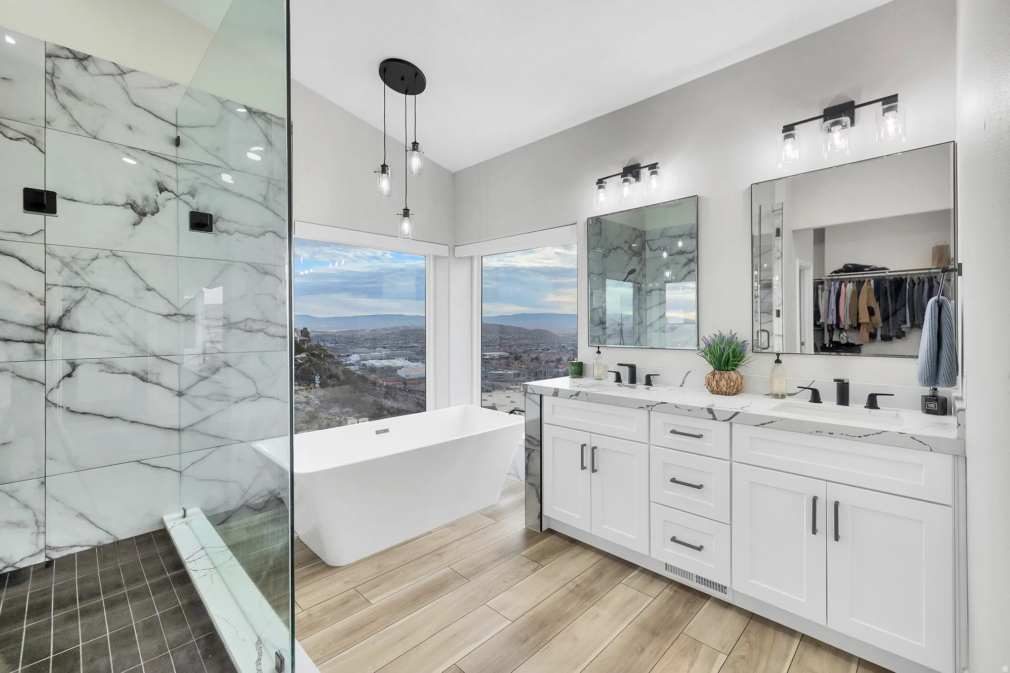 Contemporary bathroom featuring a freestanding soaking tub, expansive windows, dual vanity with undermount sinks, and a glass-enclosed shower with large format tile