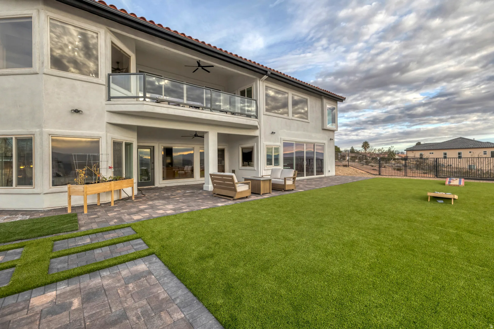 Spacious backyard featuring an artificial turf lawn and a paver patio with a covered outdoor area