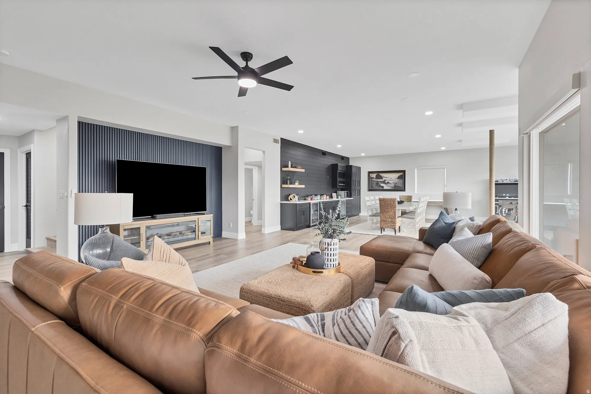 Spacious open-concept living area featuring light wood-finish flooring, recessed lighting, and a modern ceiling fan