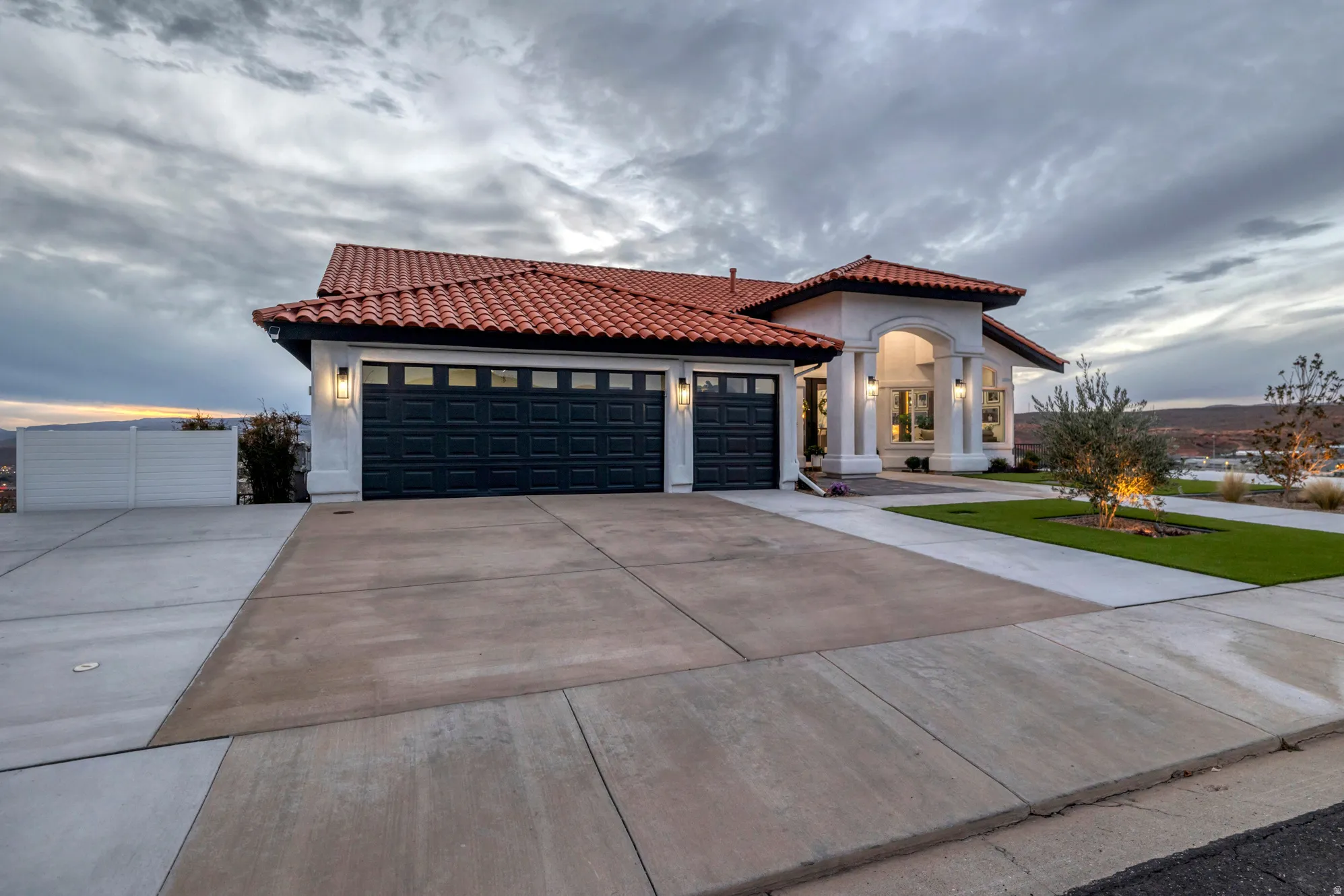Mediterranean-style exterior featuring a red tile roof, white stucco facade, and an arched entry porch