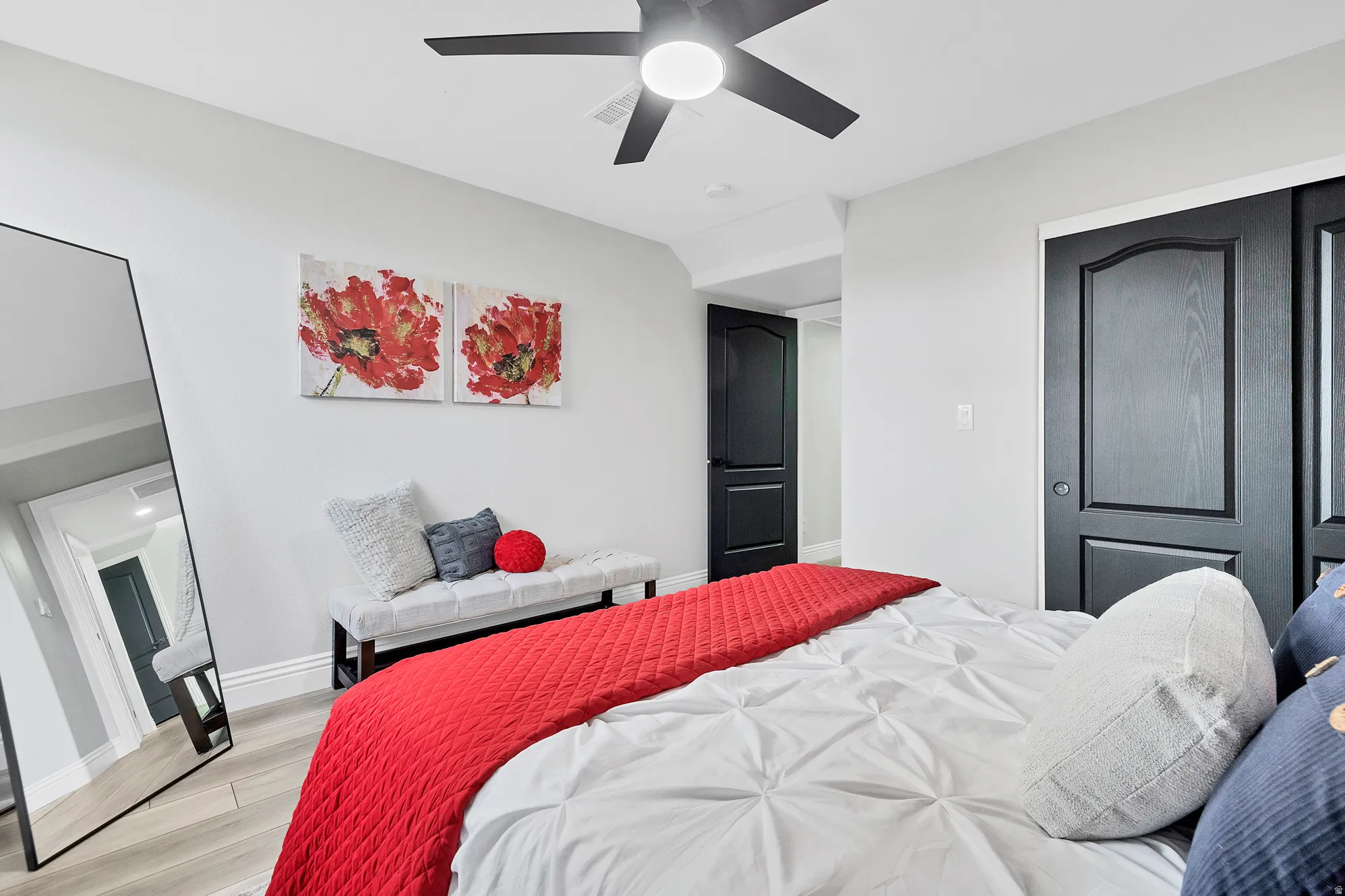 Contemporary bedroom featuring light wood-finish flooring and a ceiling fan with integrated lighting