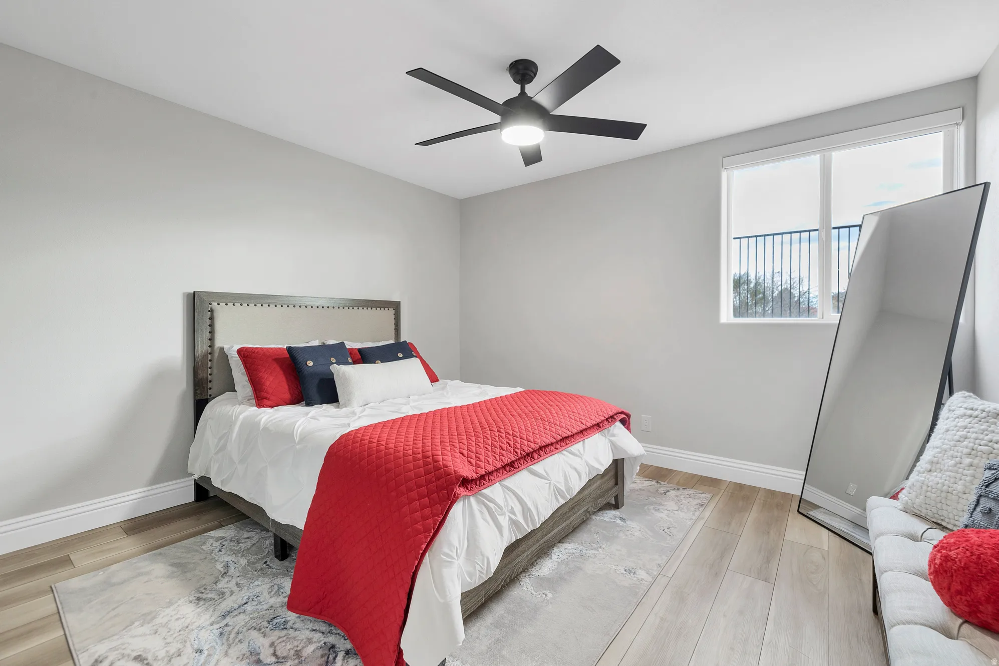 Bright room featuring wood-finish flooring, a contemporary ceiling fan with integrated lighting, and a large window with a balcony railing visible