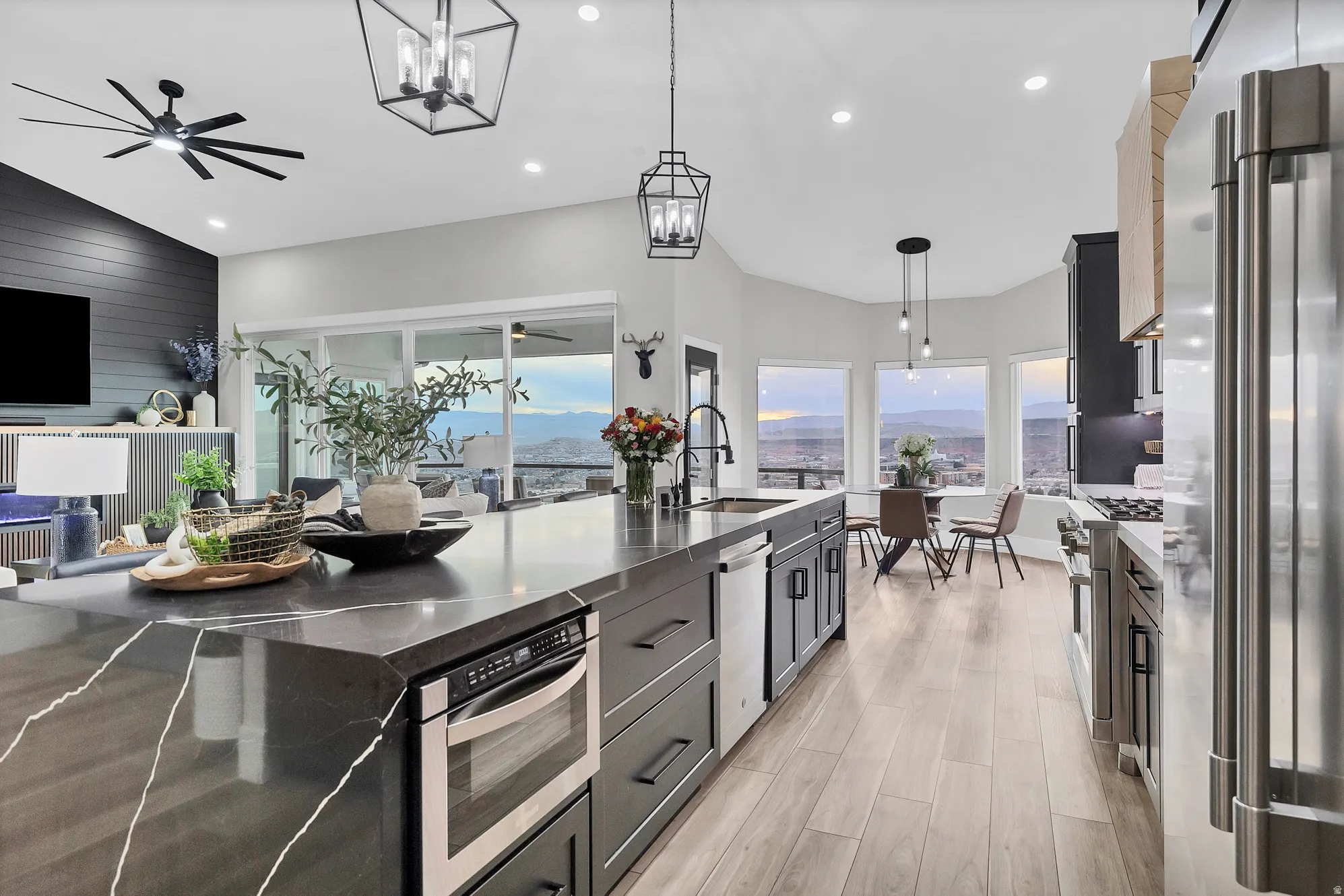 Spacious open-concept kitchen featuring an oversized island with integrated microwave, stainless steel appliances, wood-finish flooring, and ample natural light from multiple windows and a sliding glass door
