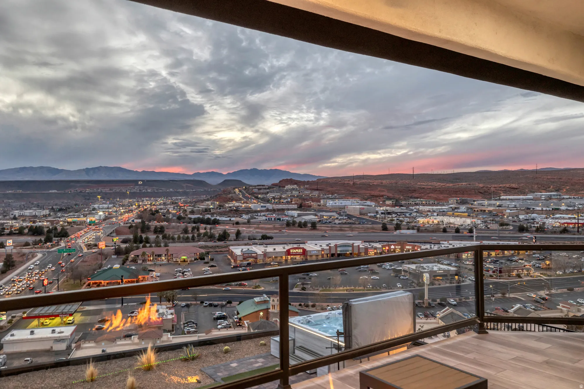 Expansive outdoor terrace featuring glass panel railing, wood-finish flooring, and a large hot tub