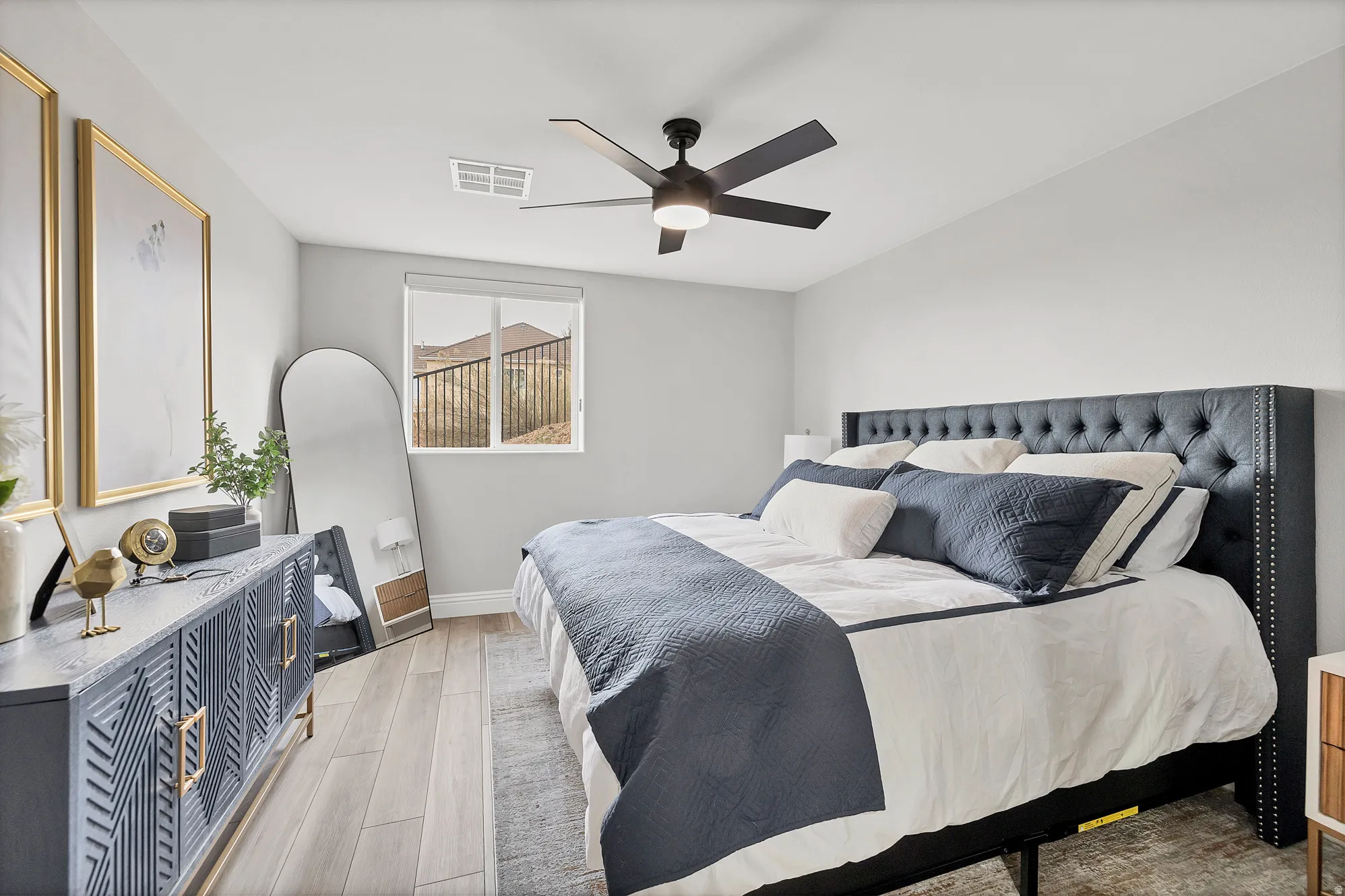 Spacious room featuring wood-finish flooring, light grey wall paint, and a large window with a roller shade