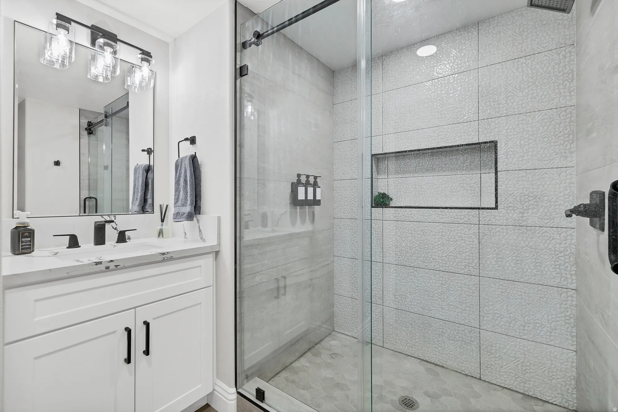 Modern bathroom featuring a frameless glass shower enclosure with a textured tile surround and an integrated shower niche