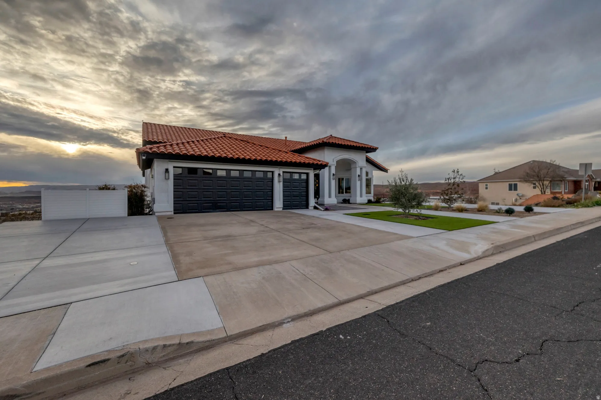Mediterranean-inspired architecture featuring a red barrel tile roof, white stucco exterior, and a grand arched entryway