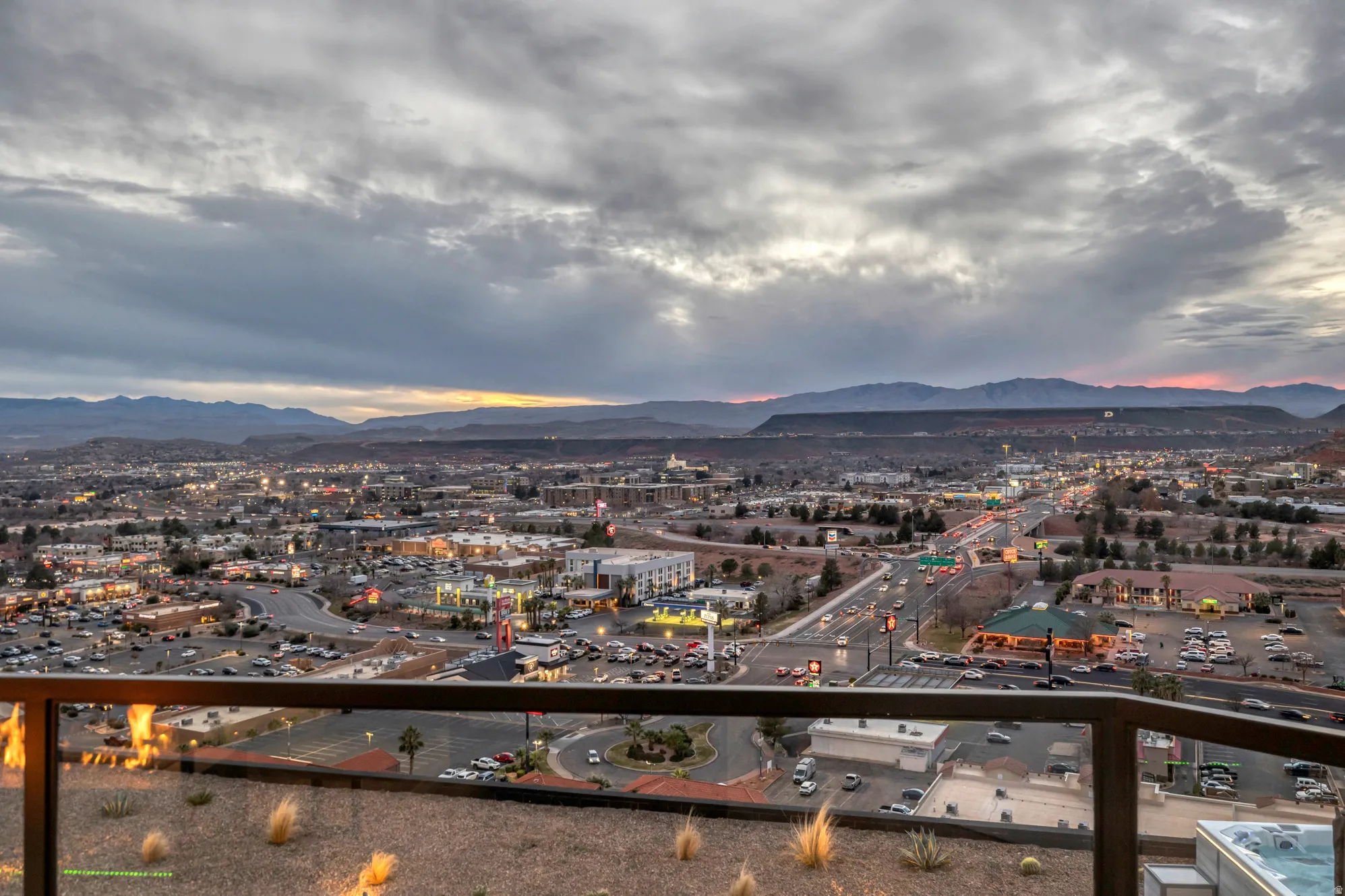 Panoramic city and mountain backdrop from a glass-paneled balcony