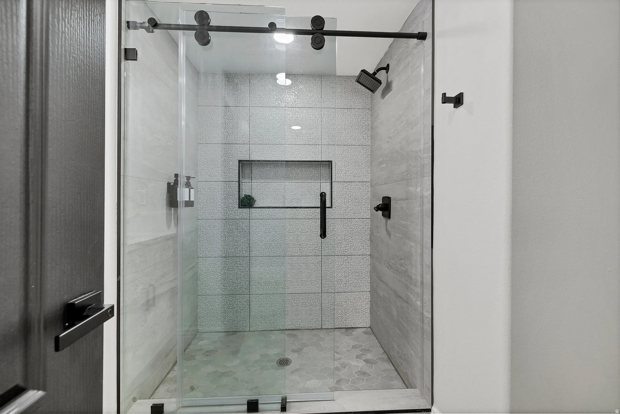 Walk-in shower featuring a frameless glass enclosure with matte black hardware