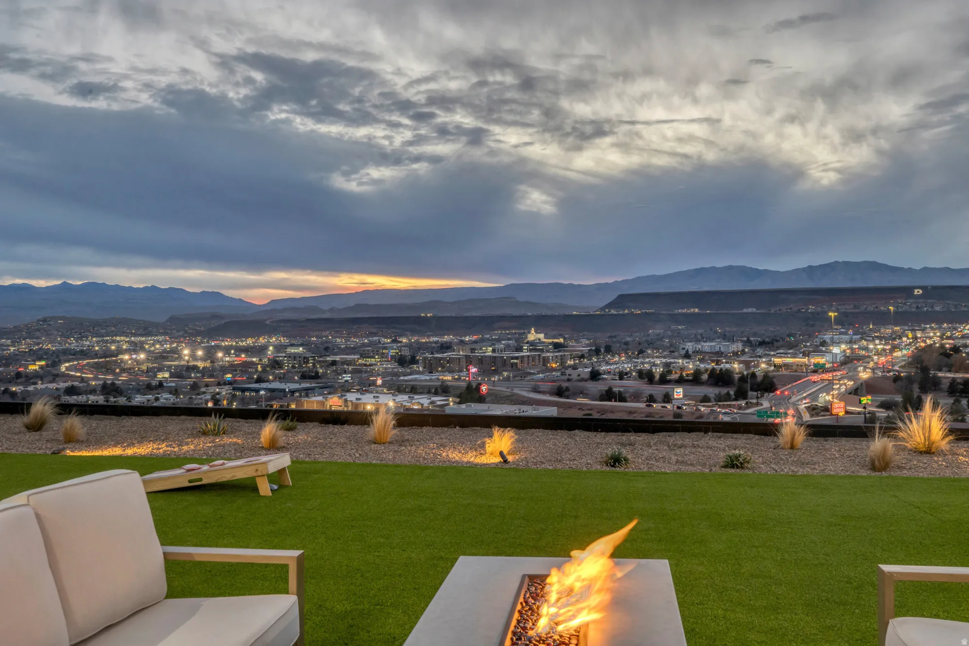 Expansive outdoor living area featuring a fire pit, artificial turf, and a gravel border with integrated lighting