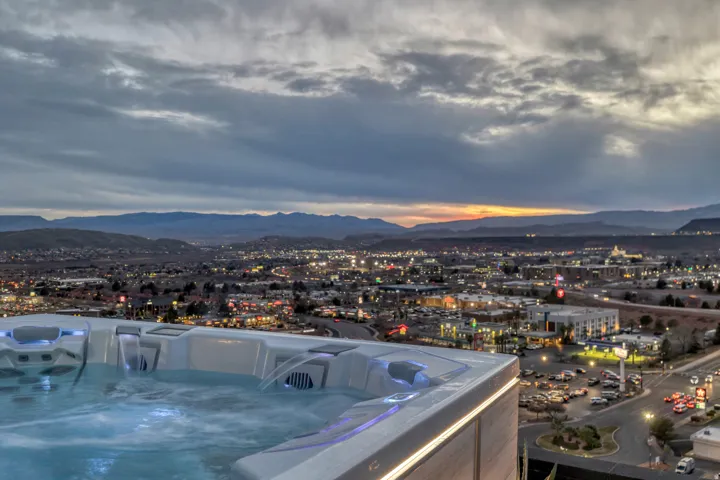 Rooftop hot tub with integrated lighting and water features, offering expansive city and mountain scenery