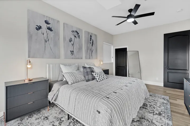 Bedroom featuring a contemporary ceiling fan, light-colored walls, and wood-finish flooring