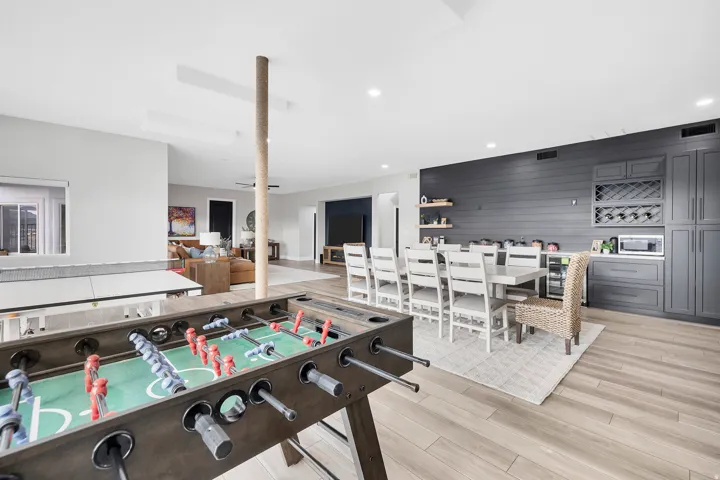 Open-concept entertainment area featuring light wood-finish flooring, recessed lighting, and a neutral color palette