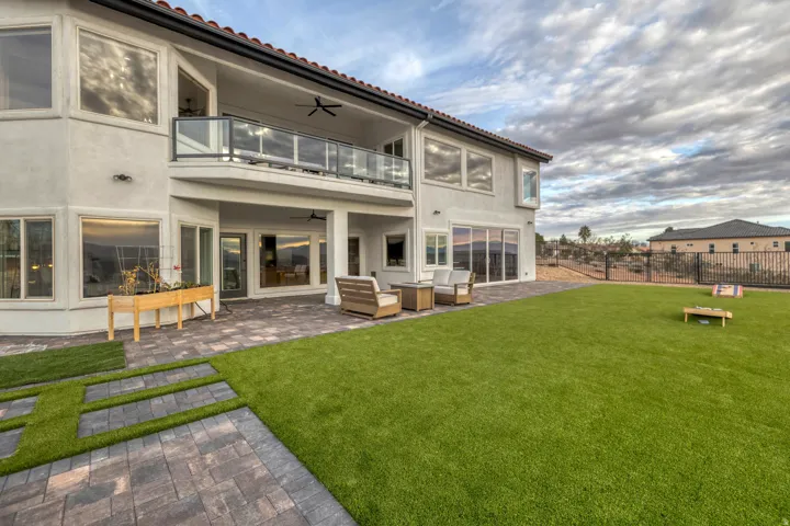 Spacious backyard featuring an artificial turf lawn and a paver patio with a covered outdoor area