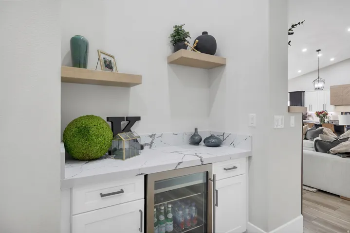 Integrated wet bar featuring white cabinetry, a stone-finish countertop, and a built-in beverage refrigerator