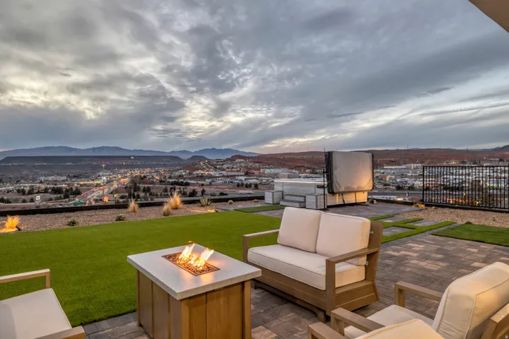 Outdoor patio featuring paver flooring, a built-in fire pit, artificial turf, low-maintenance landscaping, and surrounding mountain scenery