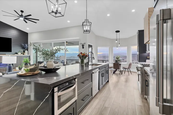 Spacious open-concept kitchen featuring an oversized island with integrated microwave, stainless steel appliances, wood-finish flooring, and ample natural light from multiple windows and a sliding glass door