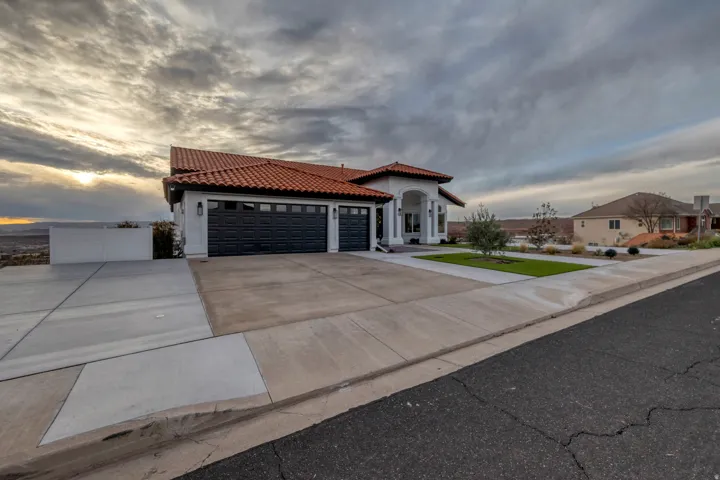 Mediterranean-inspired architecture featuring a red barrel tile roof, white stucco exterior, and a grand arched entryway