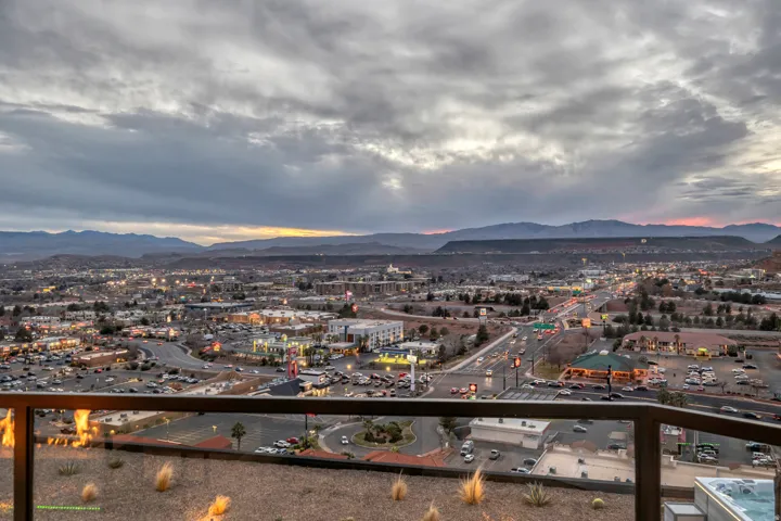 Panoramic city and mountain backdrop from a glass-paneled balcony