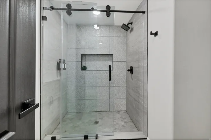 Walk-in shower featuring a frameless glass enclosure with matte black hardware